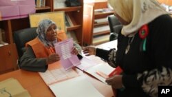 (FILE) An election worker explains a ballot to a woman at a polling center in Tripoli, Libya, June 2014.