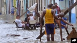 In a photo released by Granma, men play dominoes in the middle of a flooded street as others pull broken furniture from calf-high water in the aftermath Hurricane Irma, in Havana, Cuba, Sept. 10, 2017.