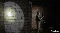 Un combatiente ucraniano, del batallón Carpathian Sich, comprueba su arma en un búnker en la región de Járkov, el 1 de julio de 2022.