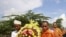 A Buddhist monk from Japan, front right, chants together with a Cambodian Buddhist monk, center, and a Cambodian Muslim, left, as they carry a wreath of flowers to lead a march at Choeung Ek, a former Khmer Rouge killing field, some 16 kilometers (10 mile