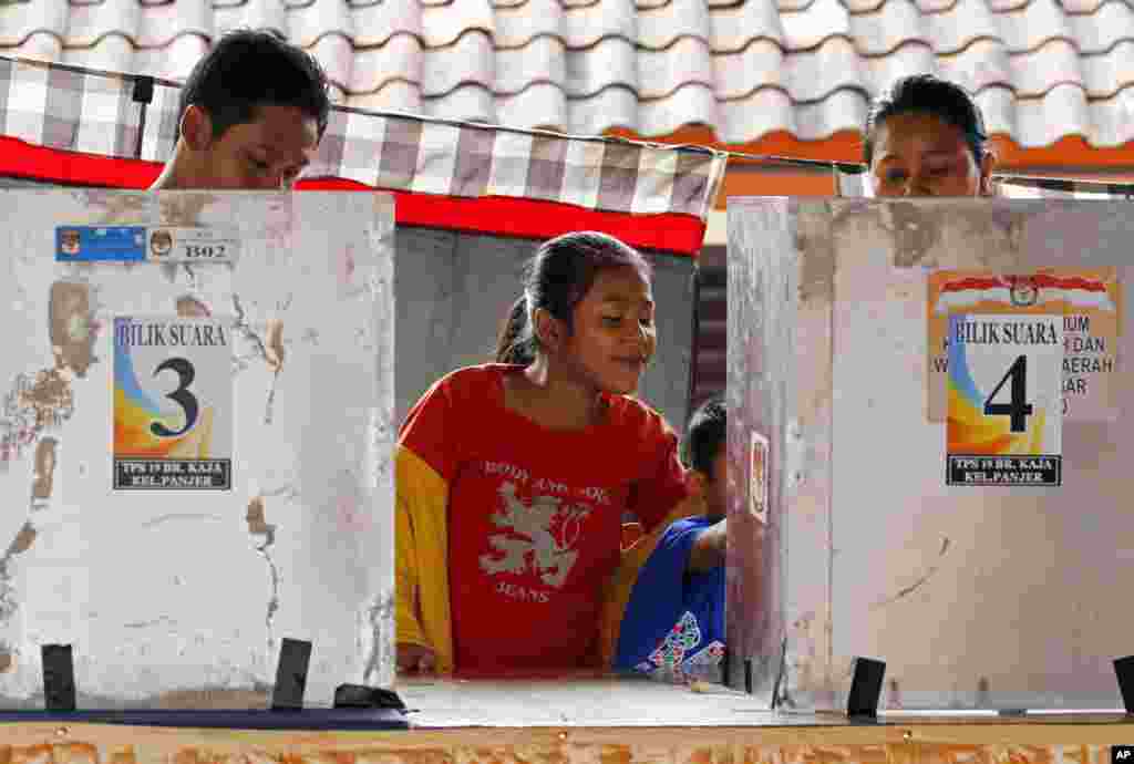 Anak-anak menunggu orangtuanya memilih di sebuah TPS di Bali (9/7).&nbsp;(AP/Firdia Lisnawati)