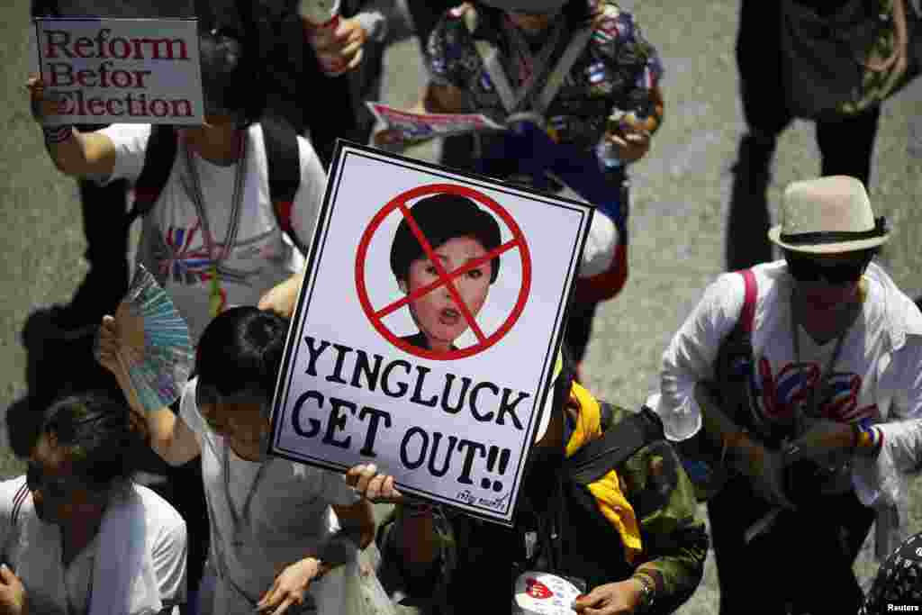 An anti-government protester carries a placard with a picture of Thai Prime Minister Yingluck Shinawatra as protesters march through central Bangkok, March 29, 2014.