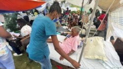 Una mujer es atendida por un miembro del personal médico afuera de un hospital después del terremoto de magnitud 7.2 del sábado, en Les Cayes, Haití, el 16 de agosto de 2021.
