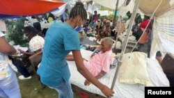 Una mujer es atendida por un miembro del personal médico afuera de un hospital después del terremoto de magnitud 7,2 del sábado, en Les Cayes, Haití, el 16 de agosto de 2021.
