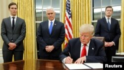 도널드 트럼프(앞) 미국 대통령이 지난 20일 백악관 오벌오피스에서 제러드 쿠슈너(왼쪽) 백악관 선임고문, 마이크 펜스(왼쪽 두번째) 부통령 등이 배석한 가운데 '오바마케어' 관련 규정을 포함한 첫 행정명령에 서명하고 있다. 