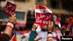 Protesters opposing Egyptian President Mohamed Mursi hold up signs during a protest demanding that Mursi resign at Tahrir Square in Cairo, July 2, 2013. 