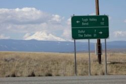FILE - This sign near Dufur, Oregon, shows distances to the nearest towns, March 20, 2020. Rural residents fear the spread of coronavirus to areas with scarce medical resources.