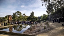 Orang-orang duduk di samping kolam refleksi saat berlangsungnya upacara menandai ulang tahun ke-25 pembunuhan 35 orang di negara bagian Tasmania, di Port Arthur, Australia, Rabu, 28 April 2021.