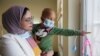 FILE—Sabreen Abdel Zahra Hussein, 26 year old cancer survivor who works as a volunteer, at the same hospital where she received her treatment, carries a child who suffers from cancer, at a Hospital in Basra, Iraq March 6, 2024.