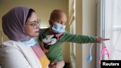 FILE—Sabreen Abdel Zahra Hussein, 26 year old cancer survivor who works as a volunteer, at the same hospital where she received her treatment, carries a child who suffers from cancer, at a Hospital in Basra, Iraq March 6, 2024.