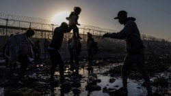 Joiner, un migrante venezolano de 22 años, entrega a un compatriota a su hija Ivanna, de tres años, mientras cruzan el río Grande en busca de un punto de entrada a EEUU desde la Ciudad Juárez, México, al amanecer del 20 de abril de 2024.