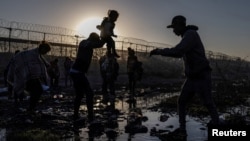 Joiner, un migrante venezolano de 22 años, entrega a un compatriota a su hija Ivanna, de tres años, mientras cruzan el río Grande en busca de un punto de entrada a EEUU desde la Ciudad Juárez, México, al amanecer del 20 de abril de 2024.