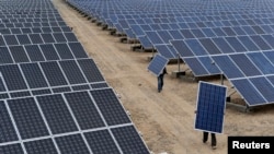 Employees carry solar panels at a solar power plant in Xinjiang, China (2012 photo)