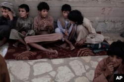 In this July 27, 2018, photo, 14 year-old Abdel Hamid, second right, and 14 year-old Morsal, third right, sit at a camp for displaced persons where they took shelter, in Marib, Yemen. (AP Photo/Nariman El-Mofty)