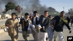 Afghans carrying a man, who got wounded following an attack on UN's office during a demonstration to condemn the burning of a copy of the Muslim holy book by a Florida pastor, in Mazar-i- Sharif north of Kabul, Afghanistan on April. 1, 2011.