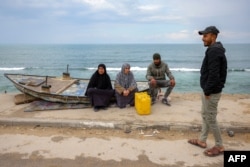 Ljudi sjede pored čamca na obali Sredozemnog mora u kampu Shati za palestinske izbjeglice sjeverno od grada Gaze 11. februara 2025.