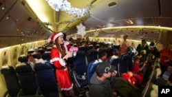 Flight attendant Kaori Kiguradze welcomes participants during the United Airlines annual "fantasy flight" to a fictional North Pole at Denver International Airport, in Denver, Colorado, Dec. 14, 2024.