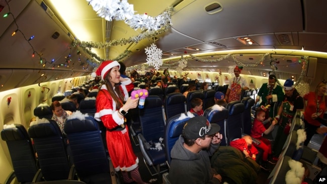 Flight attendant Kaori Kiguradze welcomes participants during the United Airlines annual "fantasy flight" to a fictional North Pole at Denver International Airport, in Denver, Colorado, Dec. 14, 2024.