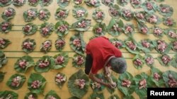 Seorang pria meletakkan daging-daging kurban dalam alas daun sebelum dibagikan untuk Iduladha di sebuah masjid di Yogyakarta, 11 Agustus 2019. (Foto: Antara/Andreas Fitri via Reuters)