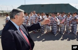 FILE - In this Feb. 4, 2009, file photo, Maricopa County Sheriff Joe Arpaio, left, orders approximately 200 convicted illegal immigrants handcuffed together and moved into a separate area of Tent City, for incarceration until their sentences are served an