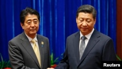 Presiden China Xi Jinping dan Perdana Menteri Jepang Shinzo Abe bersalaman dalam pertemuan di Beijing, di sela-sela KTT APEC (10/11). 