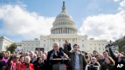 Senate Minority Leader Sen. Chuck Schumer, D-N.Y., holds hands with student activist Matt Post, right, during a student gun control advocates rally outside the Capitol Building in Washington, March 14, 2018. Students walked out of school to protest gun violence in the biggest demonstration yet of the student activism that has emerged in response to last month's massacre of 17 people at Florida's Marjory Stoneman Douglas High School. 