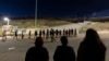 FILE - Migrants are lined up along the border walls separating Tijuana, Mexico, and San Diego, to apply for asylum with U.S authorities, May 7, 2024, in San Diego.