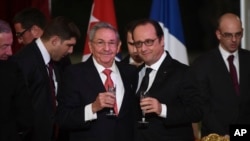 FILE - Cuban President Raul Castro (L) and French President Francois Hollande raise a glass during a state dinner at the Elysee Presidential Palace in Paris, France, Feb. 1, 2016. Castro also received a warm welcome from French business leaders.