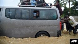 Les gens essaient de traverser la rivière La Rouyonne débordant dans la commune de Léogâne, au sud de Port-au-Prince, 5 octobre 2016.