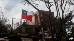 Un residente muestra una bandera chilena desde una casa incendiada después de que los incendios forestales alcanzaran su vecindario en Viña del Mar, Chile, el domingo 4 de febrero de 2024.