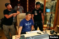 Hip-hop singers Sanjjav Baatar (L), Battogtokh Odsaikhan of a band called Fish Symboled Stamp and a sound engineer adjust a mixing console in a recording studio in Ulaanbaatar, Mongolia, June 24, 2017.