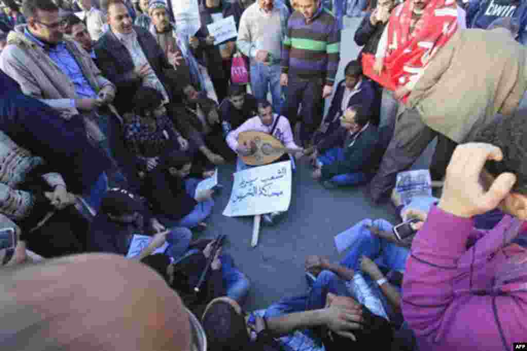 A crowd gather around a musician with a poster reading 'the people wants the vile to be put on trial' during a protest in the capital's central Tahrir, or Liberation, Square, Cairo, Egypt, Monday Jan. 31, 2011. A coalition of opposition groups called for 