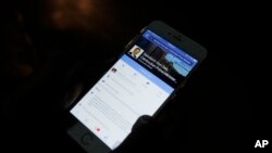 In this March 1, 2016 photo, a man views Cambodian Prime Minister Hun Sen's Facebook page on his mobile phone at a side walk in downtown Phnom Penh, Cambodia.