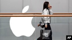 一位女士手提美國品牌Abercrombie＆Fitch的購物袋，經過在北京廣受歡迎的蘋果商店。（2019年2月26日）