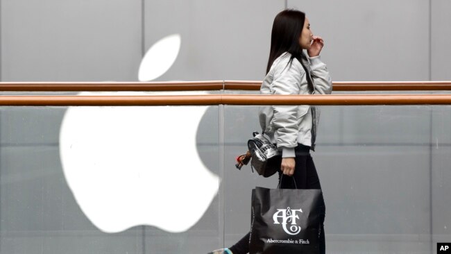一位女士手提美国品牌Abercrombie＆Fitch的购物袋，经过在北京广受欢迎的苹果商店。（2019年2月26日）
