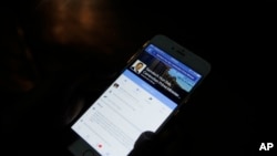 In this March 1, 2016 photo, a man views Cambodian Prime Minister Hun Sen's Facebook page on his mobile phone at a side walk in downtown Phnom Penh, Cambodia.