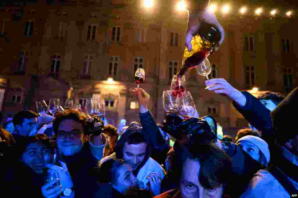 Wine is poured as people celebrate the official launch of the 2024 edition of the Beaujolais Nouveau in the streets of Lyon, in central-eastern France.