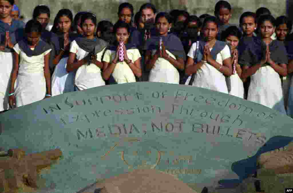 Indian students offer prayers alongside a sand sculpture paying tribute to the victims of the attack on French satirical newspaper Charlie Hebdoat, at Juhu Beach in Mumbai, Jan. 9, 2015. 