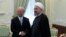 In this photo released by official website of the office of the Iranian Presidency, President Hassan Rouhani, right, and Director General of the International Atomic Energy Agency, IAEA, Yukiya Amano shake hands for media at the start of their meeting at 