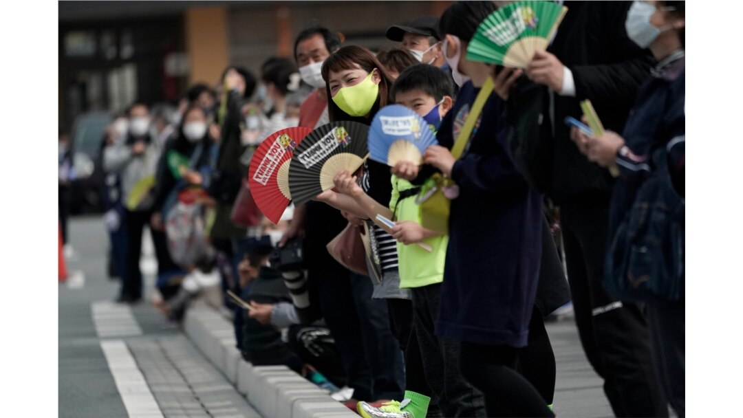 Local people wait for torchbearers to arrive at the torch relay route of the first section of the Fukushima Torch Relay in Naraha, Fukushima prefecture, northeastern Japan, March 25, 2021.