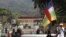 A man holds a flag during a demonstration near the presidential palace, seen in the background, in Bangui, Central African Republic, Jan. 5, 2013.