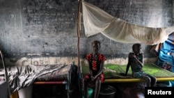 FILE - Displaced girls sit on a bed in a classroom, in a school now occupied by internally displaced people in the town of Pibor, Boma state, South Sudan, Nov. 6, 2019.