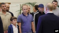 A man identified as Pablo Gonzalez, a freelance journalist from Spain, second from left with shaved head, listens to Russian President Vladimir Putin, back to a camera, speaking to released Russian prisoners on Thursday, Aug. 1, 2024.