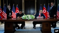 President Donald Trump and North Korean leader Kim Jong Un participate in a signing ceremony during a meeting on Sentosa Island, June 12, 2018, in Singapore. 