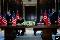 President Donald Trump and North Korean leader Kim Jong Un participate in a signing ceremony during a meeting on Sentosa Island, June 12, 2018, in Singapore.
