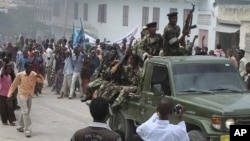 Somali government soldiers pass angry demonstrators gather at southern Mogadishu's presidential palace to protest against the anticipated resignation of the Somali prime minister in Mogadishu, Somalia, June 9, 2011