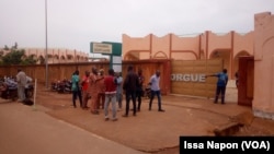 Des parents des victimes discutent devant le portail d’entrée de la morgue à Ouagadougou, Burkina Faso, le 19 juillet 2019. (VOA/Issa Napon)