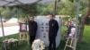 2019年10月18日，赵紫阳夫妇墓碑前摆放着出席骨灰安葬仪式的亲友们献的鲜花。赵紫阳之子赵二军（右）立于碑前。（美国之音艾伦拍摄）