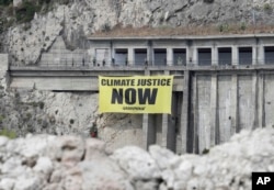 Greenpeace activists hang a banner on climate issues along a road above the beach of Isolabella, ahead of a G7 summit scheduled for May 26 and 27, in the Sicilian town of Taormina, southern Italy, May 25, 2017.