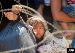 FILE - Migrants wait for Macedonian police to allow them to cross in Macedonia at the border line between Greece and Macedonia near the town of Gevgelija, Aug. 28, 2015.